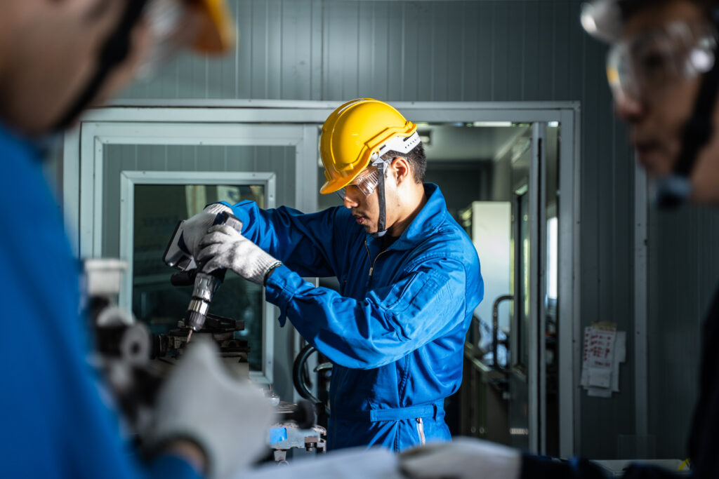 Asian mechanical workers working on milling machine.